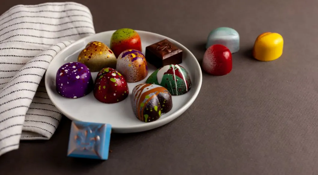 Colorful hand-painted artisan chocolates on a white plate