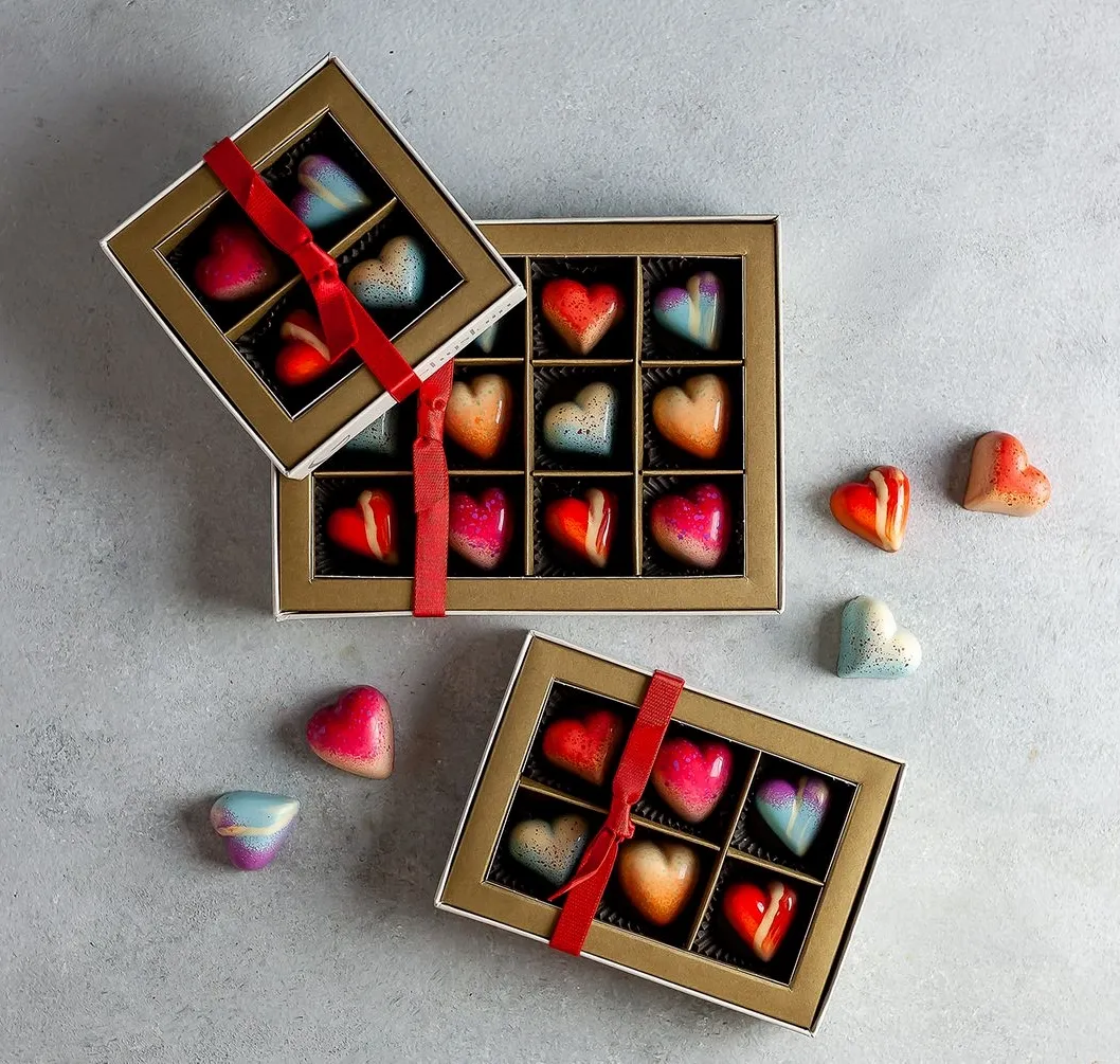 Heart-shaped artisan chocolates in three small boxes with red ribbons