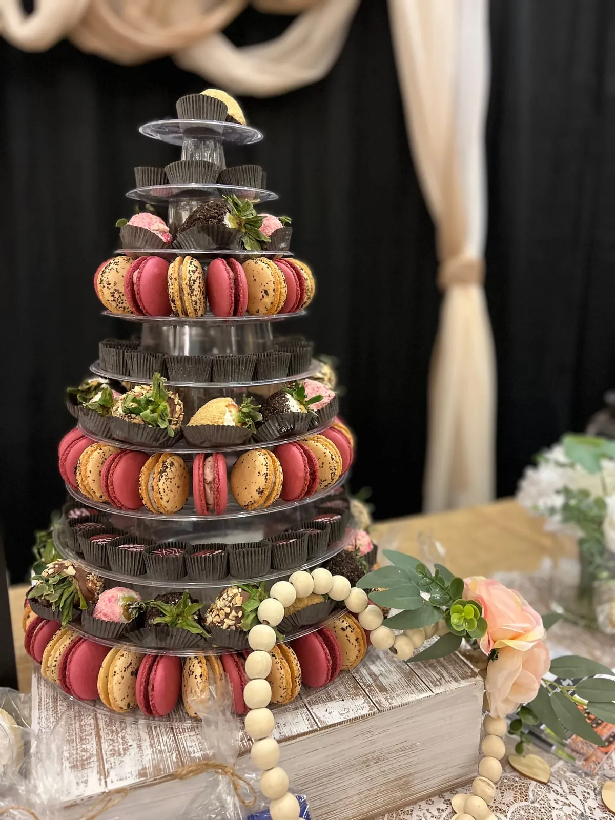 An artisan Event Tower of truffles, gourmet strawberries, and macarons styled with flowers