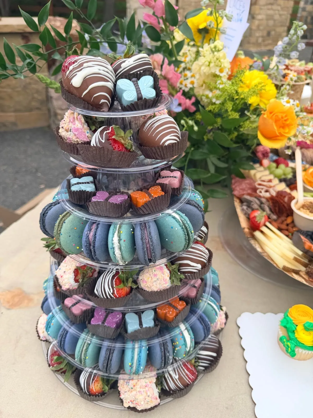 An Event Tower of truffles, strawberries, and macarons on a table set with fresh flowers