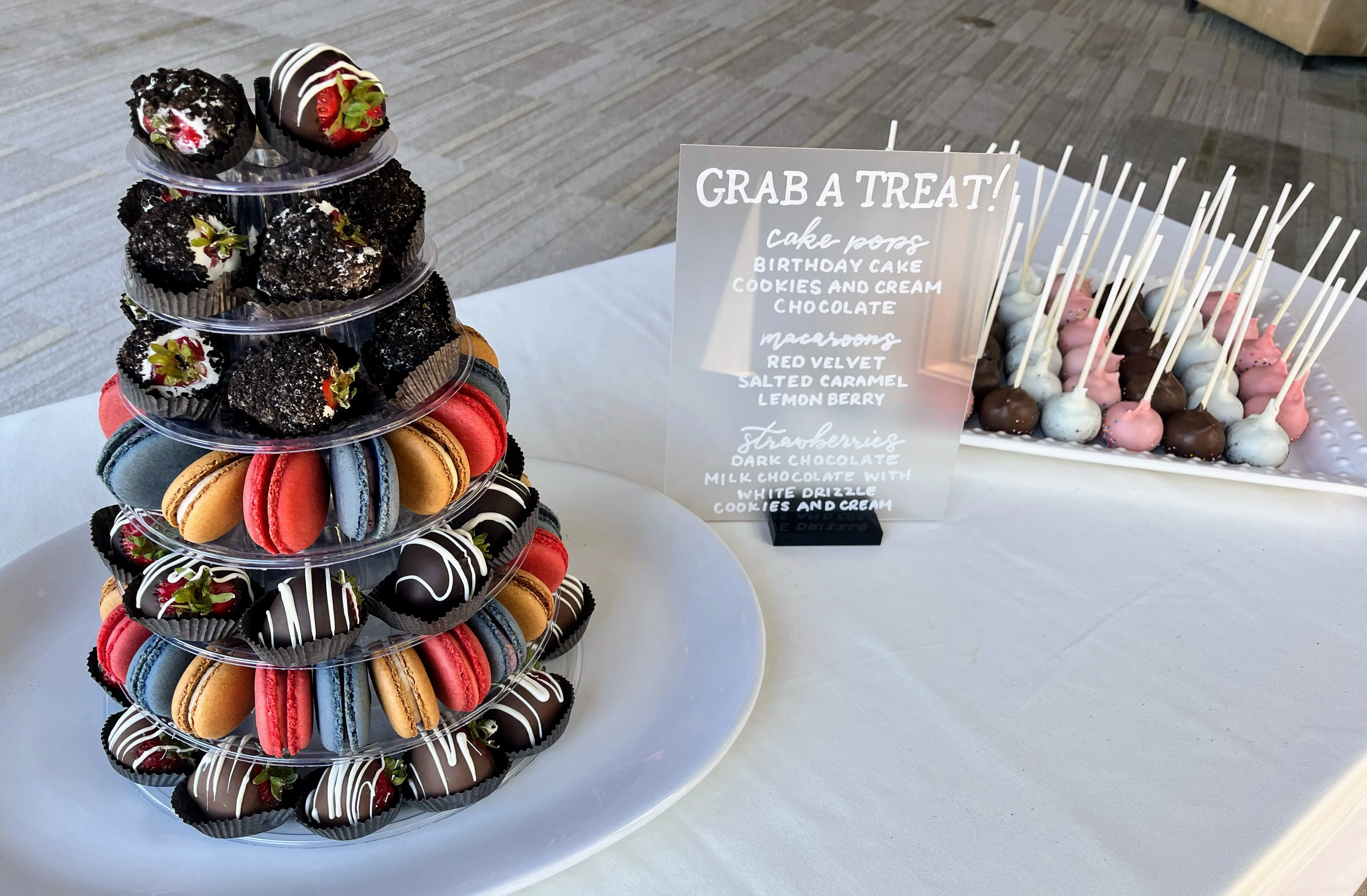 A Grab A Treat sign next to a dessert tower and cake pops at a catered event