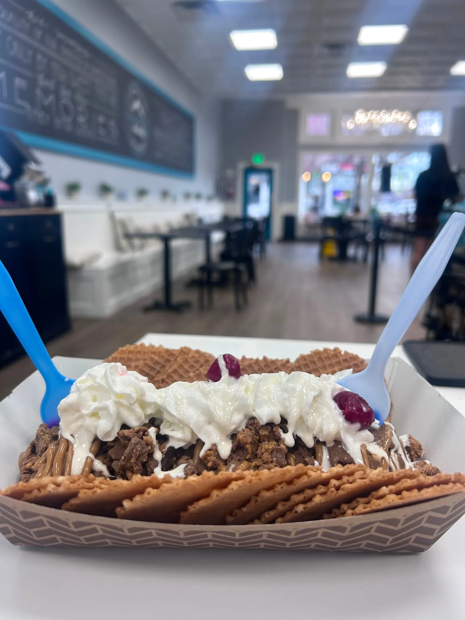A boat of HDC ice cream nachos with waffle chips, whipped cream, and cherries inside the Windsor shop