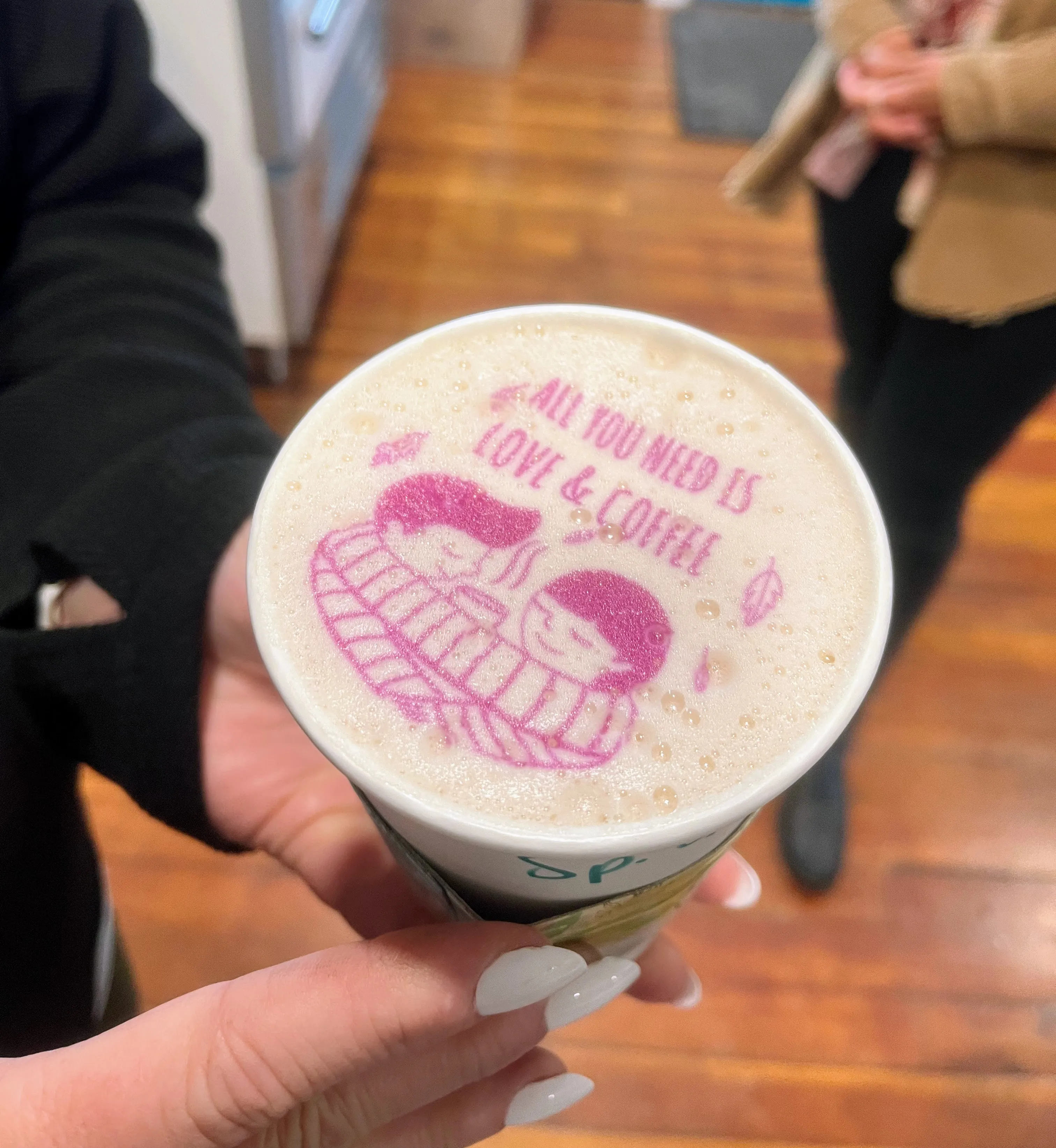 A latte with a custom All You Need Is Love and Coffee design printed on the foam