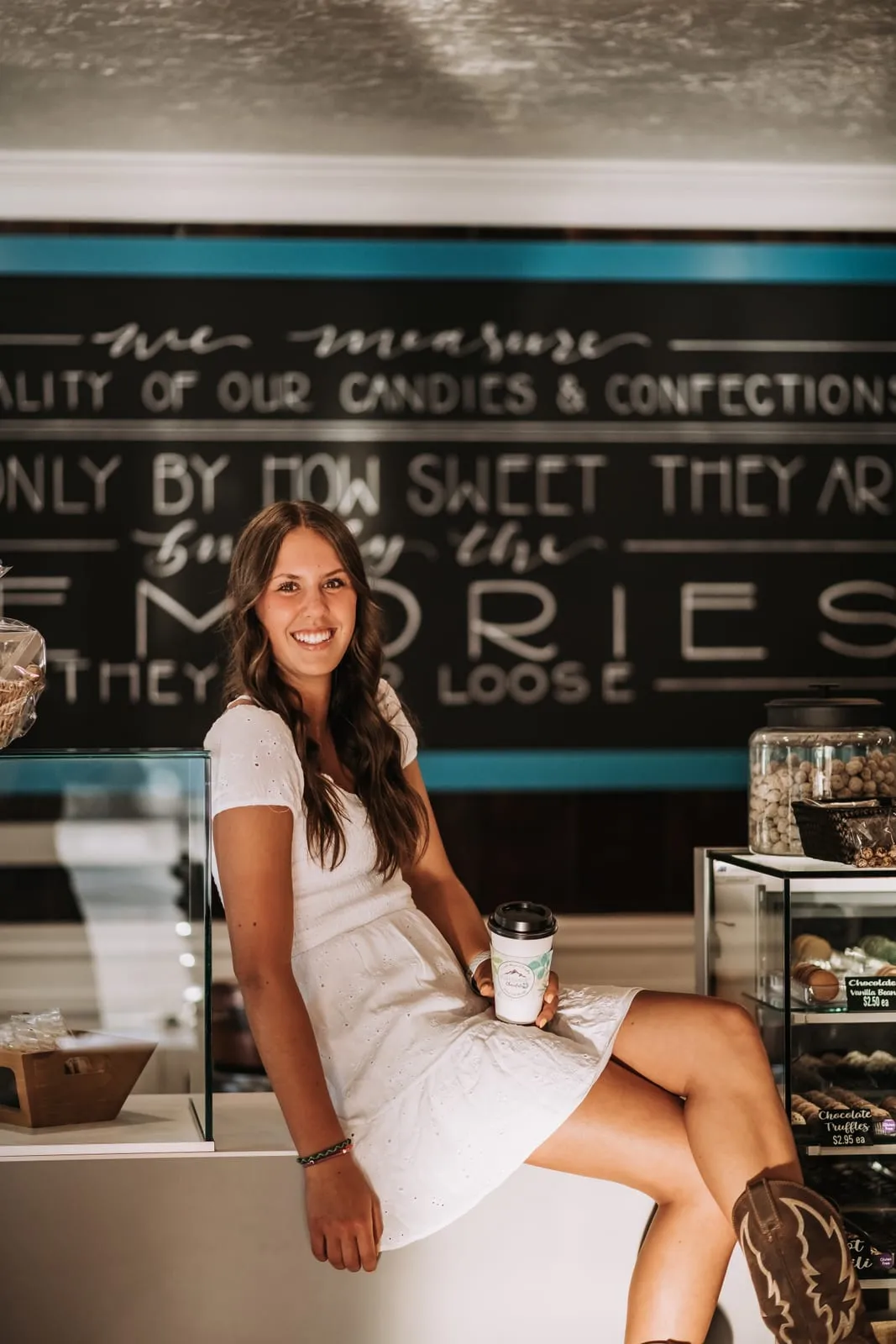 The owner of High Desert Chocolates at the counter beneath a chalkboard about making memories