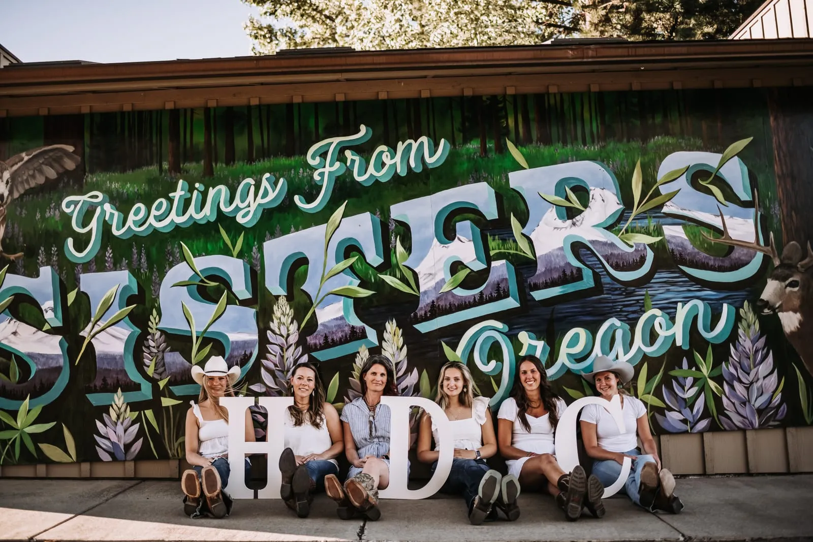 The High Desert Chocolates team in front of the Greetings From Sisters, Oregon mural