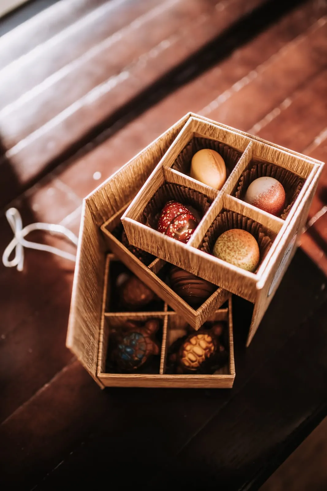 An open wooden gift box of hand-rolled artisan truffles