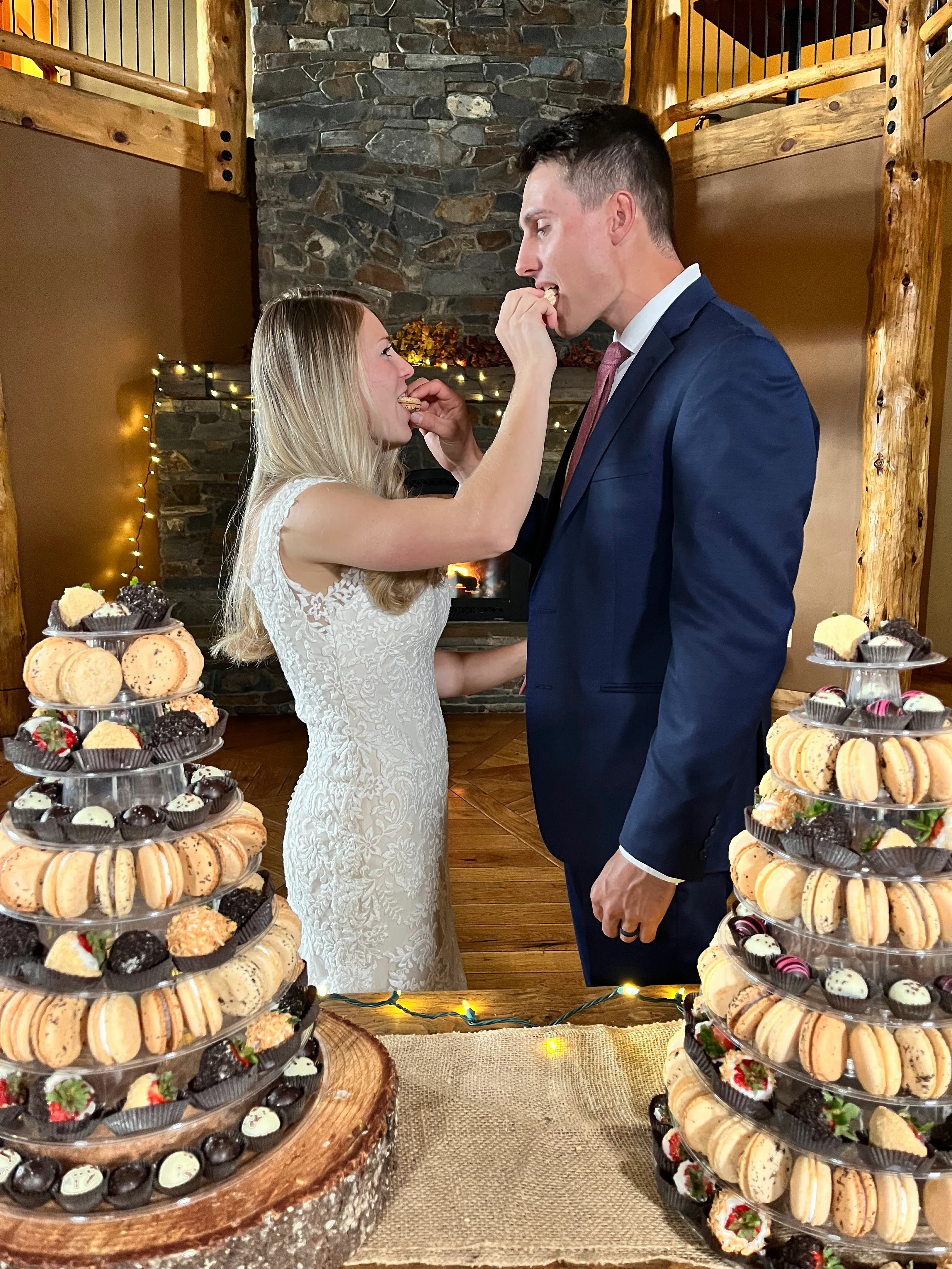 A bride and groom in front of two dessert towers at a wedding venue